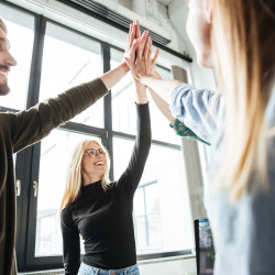 Happy colleagues in office give high five to each other